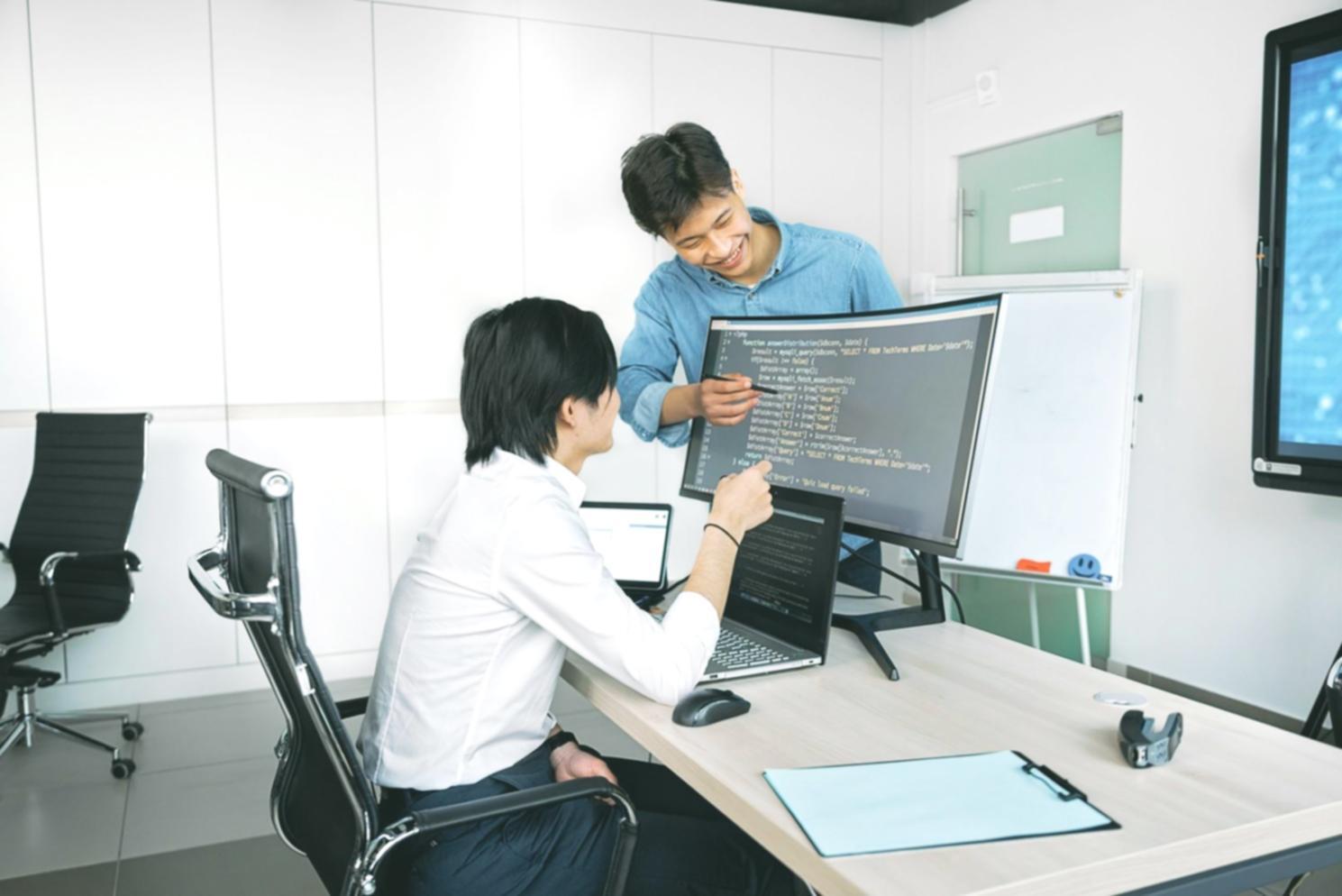 Students working on game system architecture with code displayed on screens